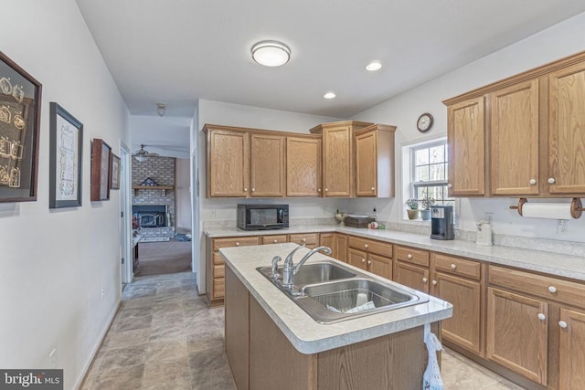 kitchen featuring sink, a fireplace, and a center island with sink