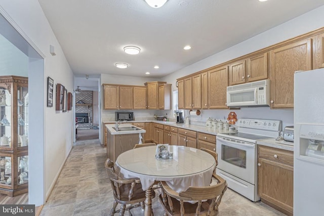 kitchen featuring white appliances, a fireplace, sink, and a kitchen island