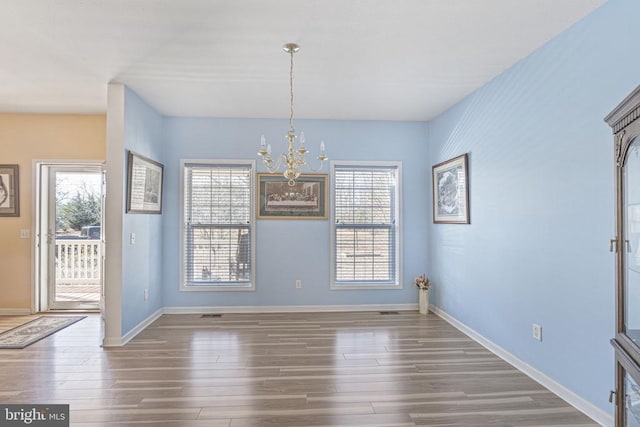 unfurnished dining area with dark wood-type flooring and a chandelier