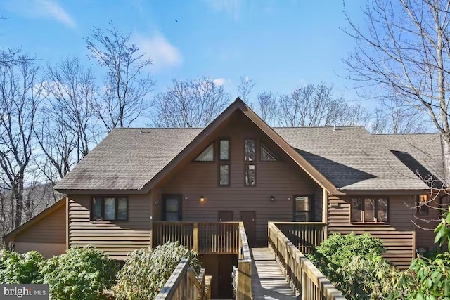 rear view of property with a shingled roof and a wooden deck