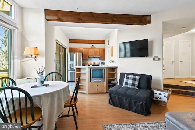 dining space with light wood-style flooring and beamed ceiling