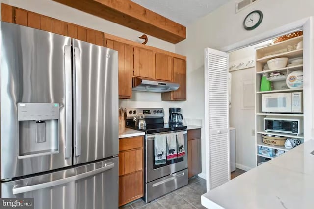 kitchen with brown cabinets, light tile patterned floors, stainless steel appliances, light countertops, and under cabinet range hood