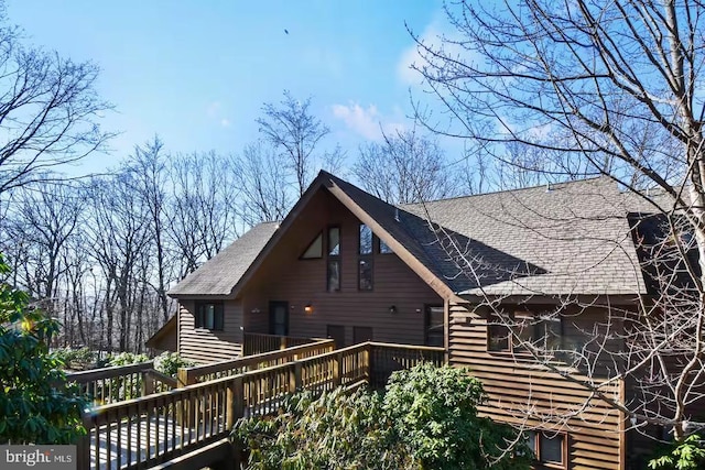 rear view of house with a deck and roof with shingles