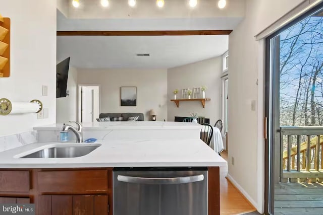 kitchen featuring light countertops, stainless steel dishwasher, plenty of natural light, and a sink