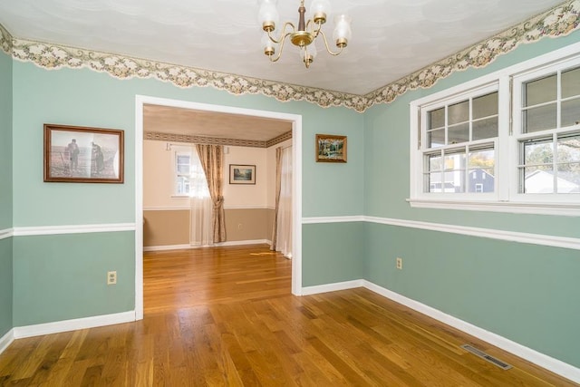 unfurnished room featuring hardwood / wood-style floors and a notable chandelier