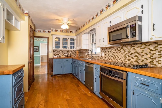 kitchen with appliances with stainless steel finishes, butcher block counters, sink, and white cabinets