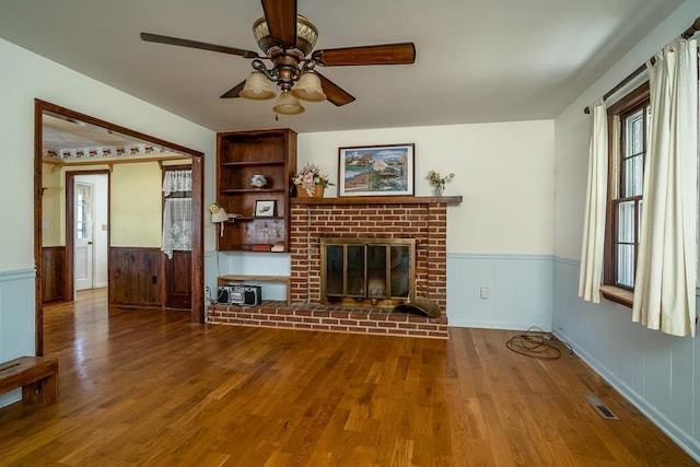 unfurnished living room with hardwood / wood-style flooring, ceiling fan, and a fireplace