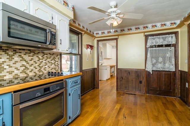 kitchen featuring white cabinetry, stainless steel appliances, wood-type flooring, blue cabinets, and wood counters