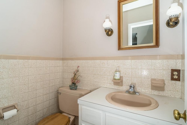 bathroom with vanity, toilet, and tile walls