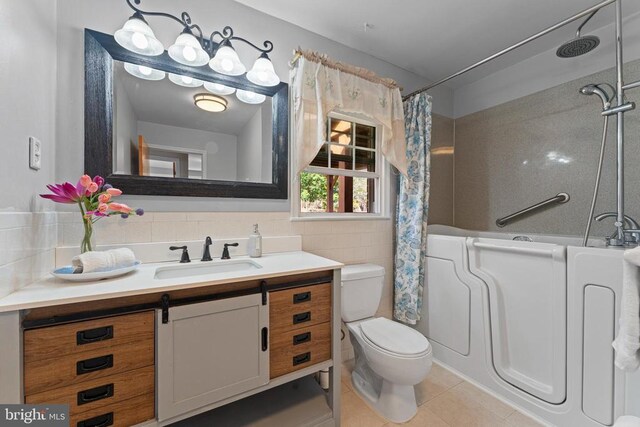 full bathroom featuring shower / bathtub combination with curtain, tile walls, vanity, tile patterned floors, and toilet