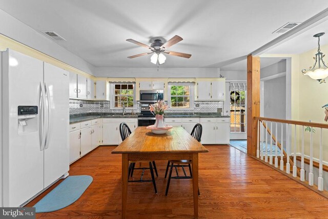 kitchen featuring decorative light fixtures, white cabinets, stainless steel appliances, light hardwood / wood-style floors, and backsplash