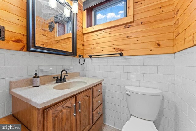 bathroom featuring vanity, tile walls, and toilet