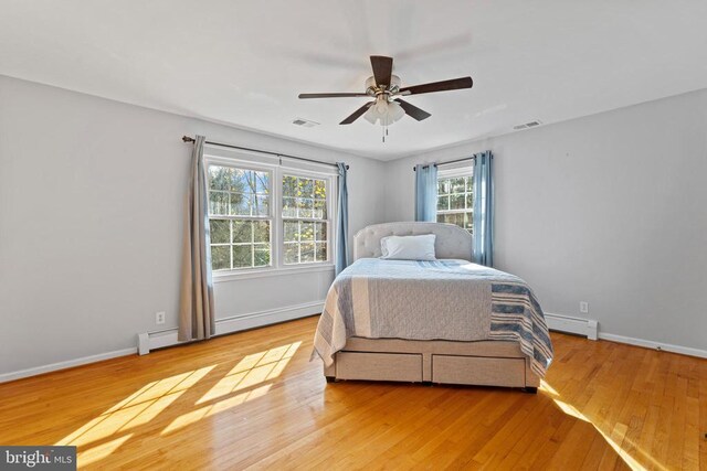 bedroom featuring a baseboard heating unit, light hardwood / wood-style floors, and ceiling fan