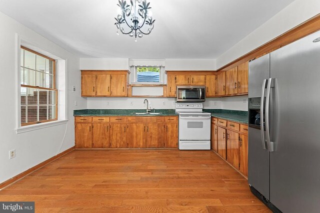 kitchen with sink, light hardwood / wood-style flooring, a chandelier, and appliances with stainless steel finishes