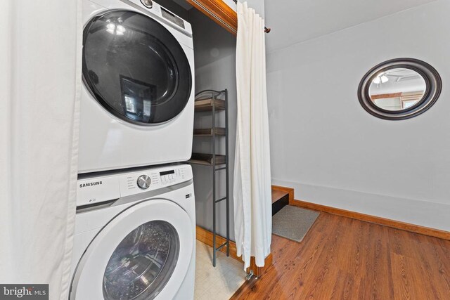 laundry area featuring stacked washer / drying machine and hardwood / wood-style floors