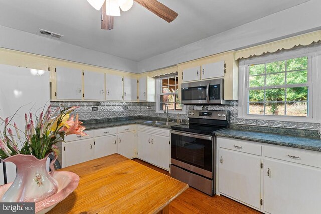 kitchen with sink, appliances with stainless steel finishes, light hardwood / wood-style floors, decorative backsplash, and white cabinets