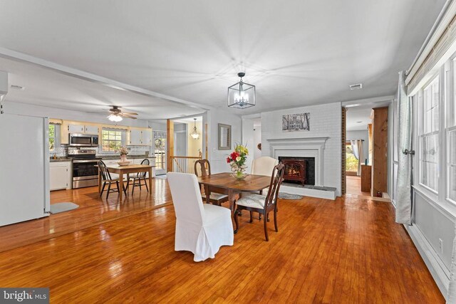 dining area with an inviting chandelier, a fireplace, and light hardwood / wood-style floors