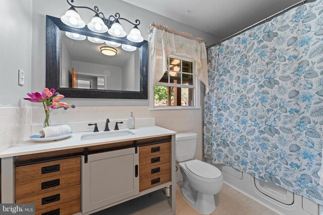 full bathroom featuring tile patterned floors, toilet, tile walls, vanity, and shower / bath combination with curtain