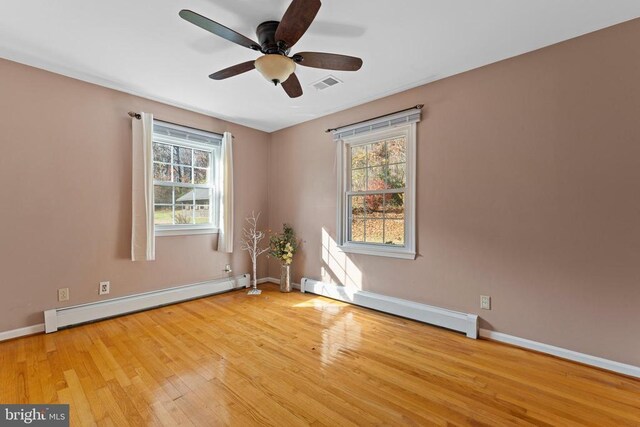 spare room featuring a baseboard radiator, a healthy amount of sunlight, and light hardwood / wood-style flooring