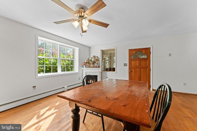 dining space with ceiling fan, light hardwood / wood-style floors, and a baseboard heating unit