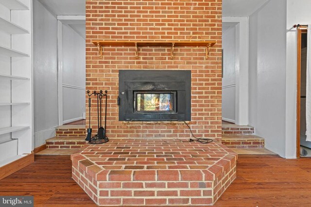 interior details with wood-type flooring and a brick fireplace