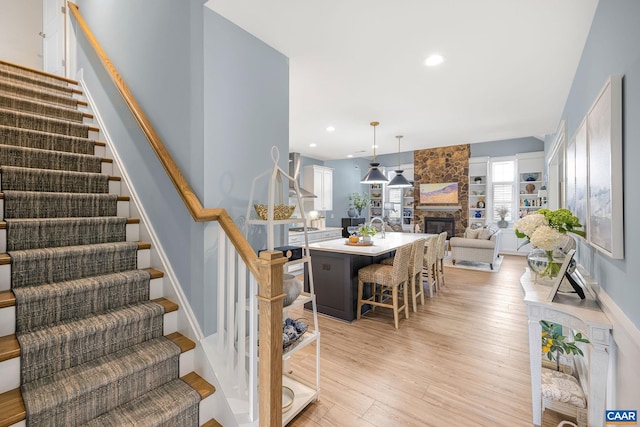 staircase with a fireplace, wood finished floors, and recessed lighting