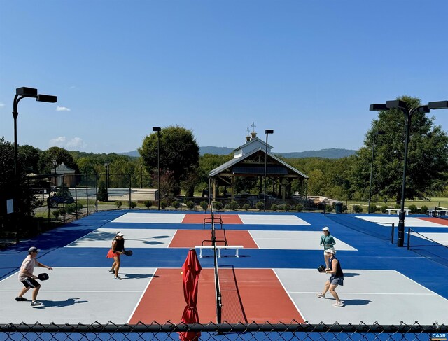 view of tennis court featuring a gazebo, fence, and a mountain view