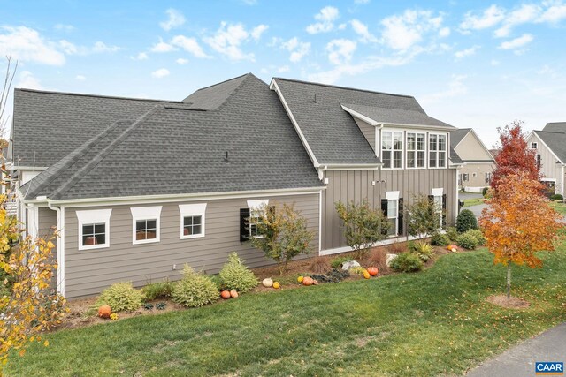 exterior space featuring a shingled roof, board and batten siding, and a lawn