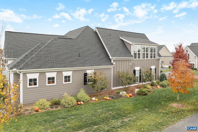 exterior space with roof with shingles, board and batten siding, and a lawn