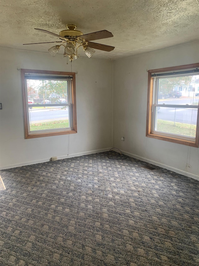 carpeted spare room with ceiling fan and a textured ceiling