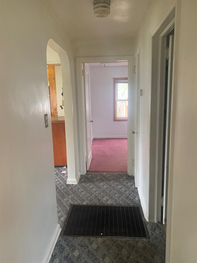 hall with dark colored carpet