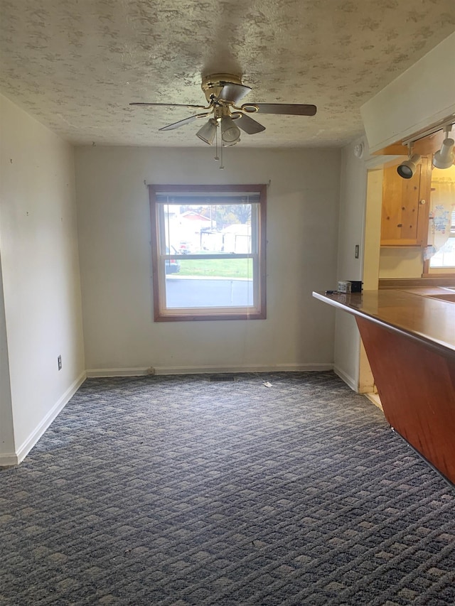 interior space featuring ceiling fan, dark carpet, and a textured ceiling