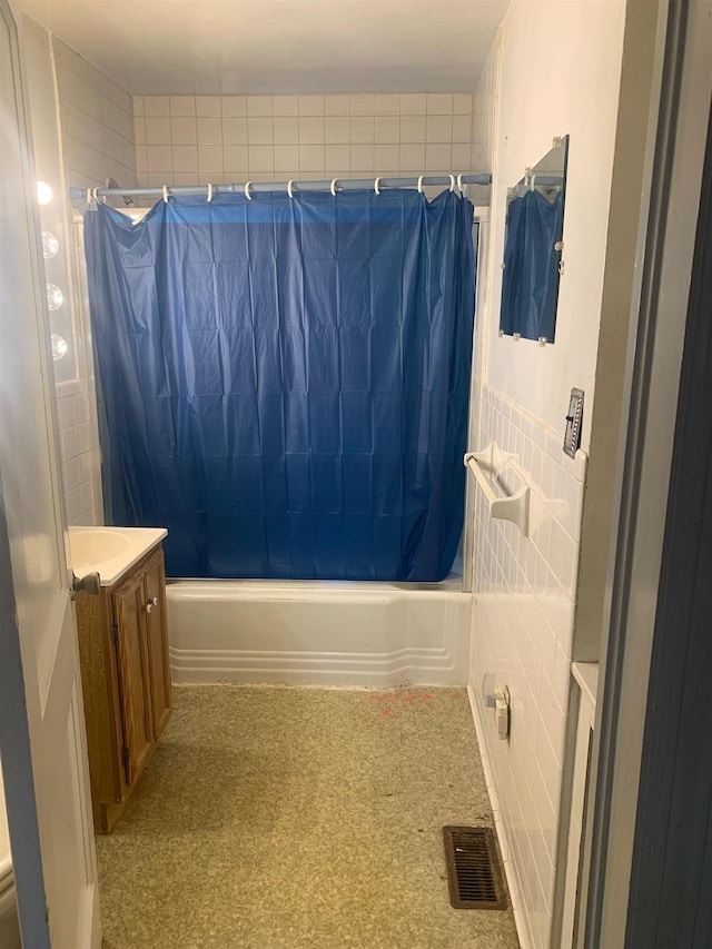 bathroom with vanity, tile walls, and shower / bath combo