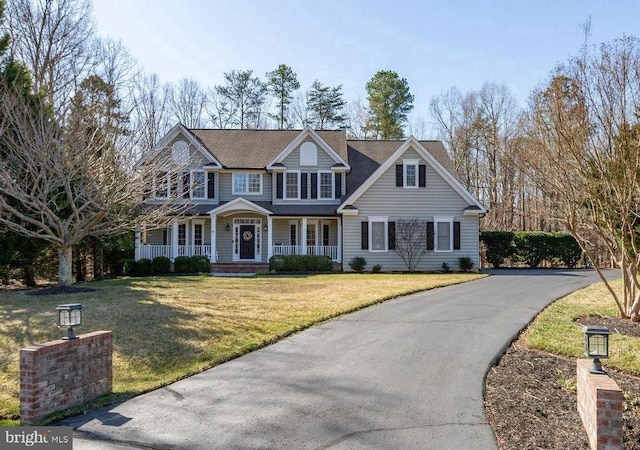 view of front facade with aphalt driveway, covered porch, and a front lawn