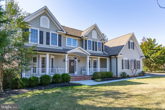 view of front of house featuring a porch, a front lawn, and roof with shingles