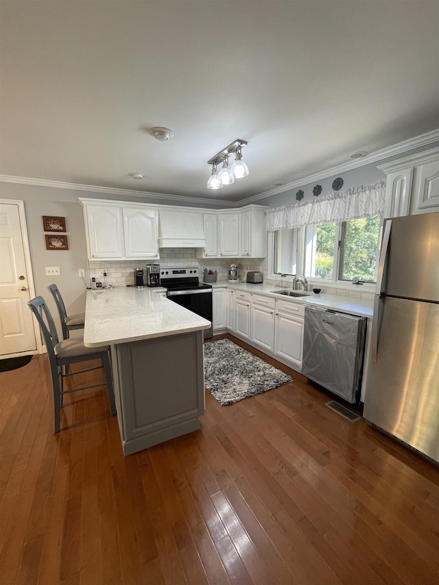 kitchen with a kitchen bar, sink, white cabinetry, ornamental molding, and appliances with stainless steel finishes