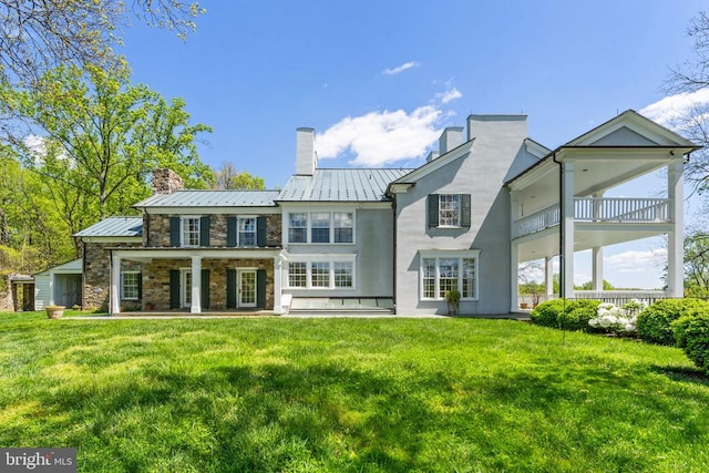 back of property featuring a lawn and a balcony