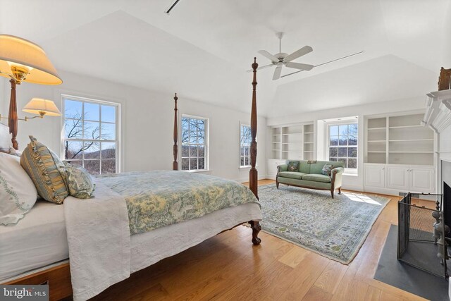 bedroom featuring ceiling fan, multiple windows, lofted ceiling, and wood-type flooring