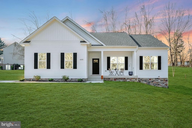 view of front of home with crawl space, roof with shingles, a porch, and a yard