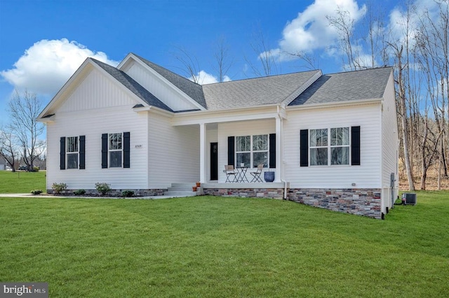 view of front facade with a porch, a front yard, central AC, and roof with shingles