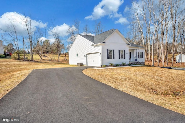 view of front of property with a garage, driveway, a front lawn, and central AC unit