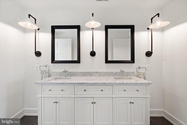 full bath featuring a sink, baseboards, and double vanity