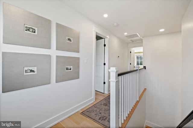 hallway with baseboards, wood finished floors, an upstairs landing, and recessed lighting