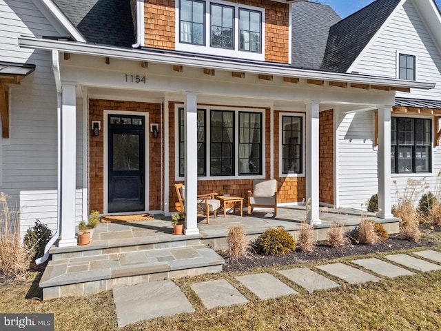 property entrance with a porch and roof with shingles