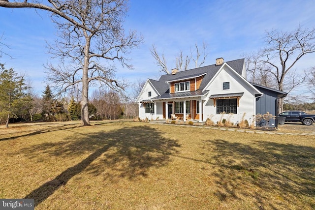 view of front of property with board and batten siding, covered porch, a chimney, and a front lawn