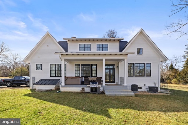 back of house with covered porch, central AC unit, and a lawn