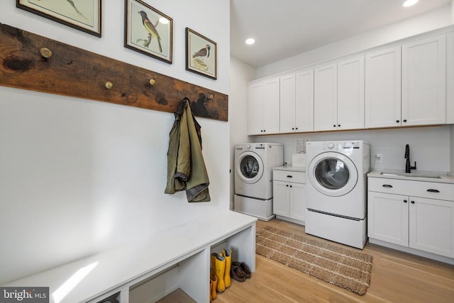 laundry area with washing machine and clothes dryer, recessed lighting, cabinet space, a sink, and light wood-type flooring