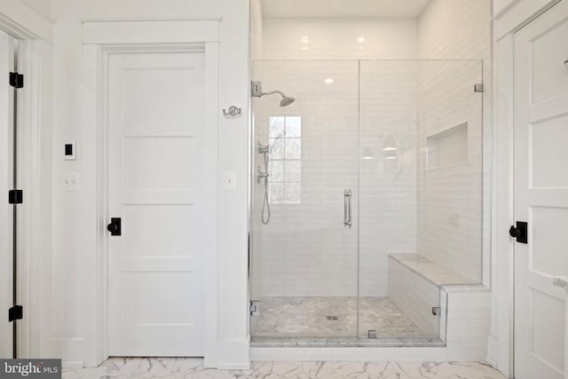 full bathroom featuring marble finish floor and a shower stall