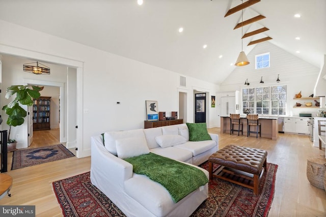 living area with recessed lighting, visible vents, high vaulted ceiling, light wood-type flooring, and beamed ceiling