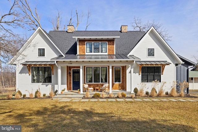 modern farmhouse with a porch, a shingled roof, a front yard, a standing seam roof, and metal roof